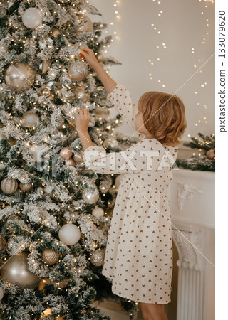 Child Decorating Christmas Tree with Joy and Wonder 133079620