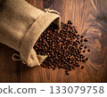 Roasted coffee beans spilling out of a burlap sack on a black background 133079758