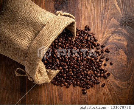 Roasted coffee beans spilling out of a burlap sack on a black background 133079758