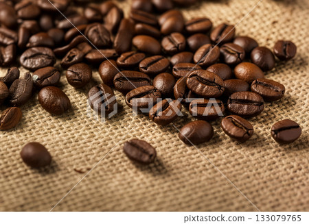 Close-up photo of fragrant roasted coffee beans spread on a linen cloth 133079765