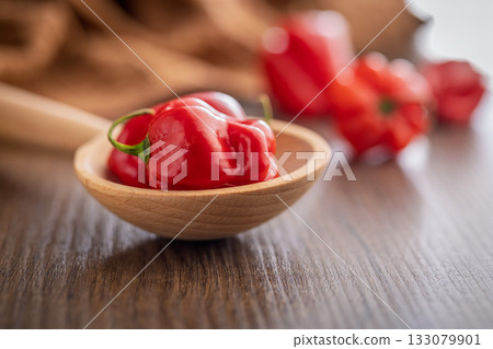 Red chili pepper habanero on wooden spoon on wooden table. Red chili pepper habanero on wooden spoon on wooden table. 133079901