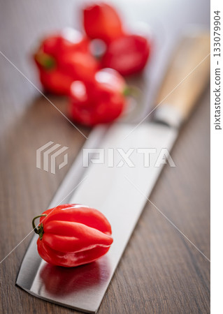 Red chili pepper habanero on knife on wooden table. 133079904