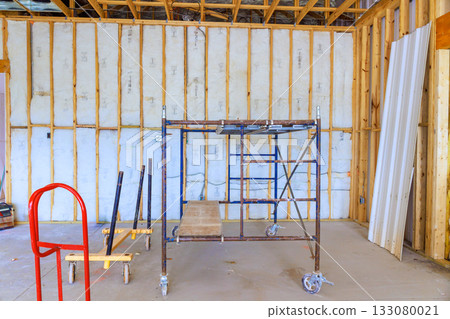 Scaffolding setup in partially constructed interior space with wooden framing unfinished walls Scaffolding setup in partially constructed interior space with wooden framing unfinished walls 133080021
