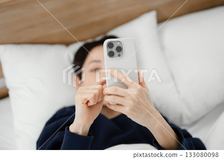 A woman watching a smartphone in bed 133080098