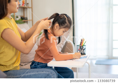 Lovely mom and little young daughter spending time together in their living room. Lovely mom and little young daughter spending time together in their living room. 133080739