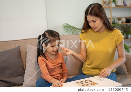 Lovely mom and little young daughter spending time together in their living room. 133080745