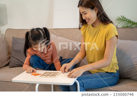 Lovely mom and little young daughter spending time together in their living room. 133080746