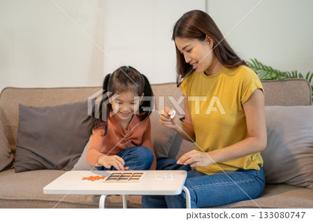 Lovely mom and little young daughter spending time together in their living room. 133080747