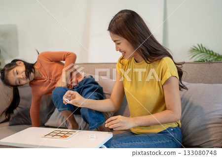 Lovely mom and little young daughter spending time together in their living room. 133080748