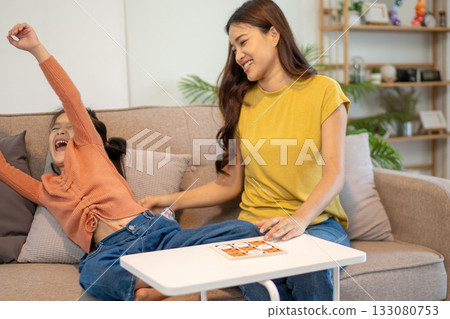 Lovely mom and little young daughter spending time together in their living room. Lovely mom and little young daughter spending time together in their living room. 133080753