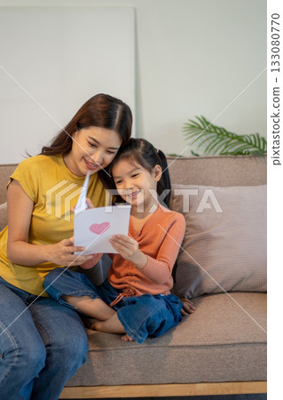Lovely mom and little young daughter spending time together in their living room. Lovely mom and little young daughter spending time together in their living room. 133080770