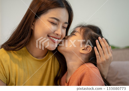 Lovely mom and little young daughter spending time together in their living room. Lovely mom and little young daughter spending time together in their living room. 133080773