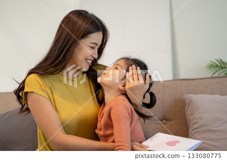 Lovely mom and little young daughter spending time together in their living room. Lovely mom and little young daughter spending time together in their living room. 133080775