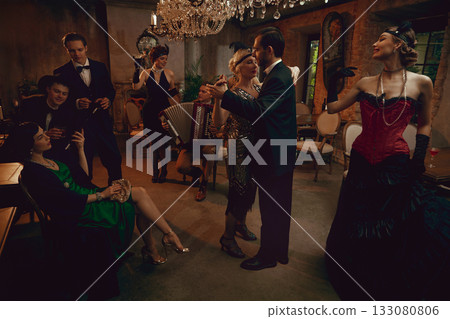 Elegant retro dance scene with couple dancing and friends relaxing in vintage restaurant Elegant retro dance scene with couple dancing and friends relaxing in vintage restaurant 133080806
