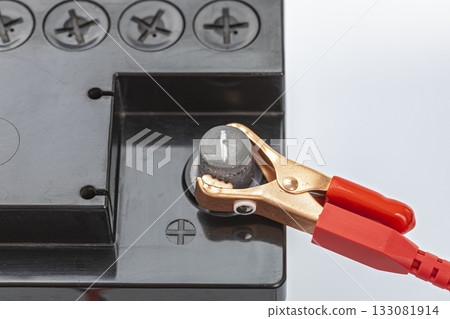Red Alligator Clip Connected to Positive Terminal of Black Car Battery, Electrical Connection and Power Supply Concept Red Alligator Clip Connected to Positive Terminal of Black Car Battery, Electrical Connection and Power Supply Concept 133081914