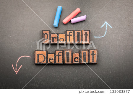 Words profit and deficit made from vintage wooden letterpress blocks with chalk arrows on blackboard Words profit and deficit made from vintage wooden letterpress blocks with chalk arrows on blackboard 133083877