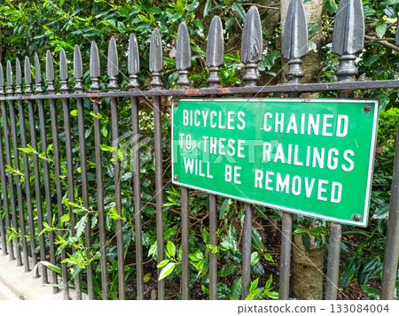 'Bicycles chained to these railings will be removed' green sign on iron fence 133084004