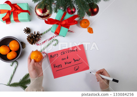 Preparing Christmas Greetings on Red Paper With Gifts and Ornaments Preparing Christmas Greetings on Red Paper With Gifts and Ornaments 133084256