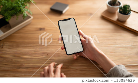 Person holding smartphone with financial transaction screen open. Mobile banking, digital finance and online payments in clean workspace setting 133084629