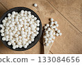 Organic tapioca pearls in black bowl on wooden table top view. Spoon with white dry tapioca pearls, cooking ingredient, gluten-free food, healthy eating. 133084656