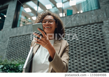 bright atrium with happy creator, female user photographing and writing in contemporary environment 133084986