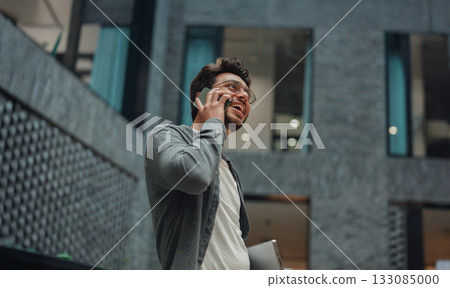 selfassured male business owner participates in phone discussion in contemporary lobby area 133085000