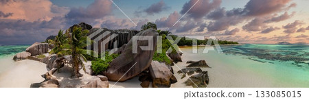 Panoramic view of Anse Source d'Argent on La Digue, Seychelles, with granite boulders, white sand, palm trees, and shallow turquoise lagoons at golden hour. Panoramic view of Anse Source d'Argent on La Digue, Seychelles, with granite boulders, white sand, palm trees, and shallow turquoise lagoons at golden hour. 133085015