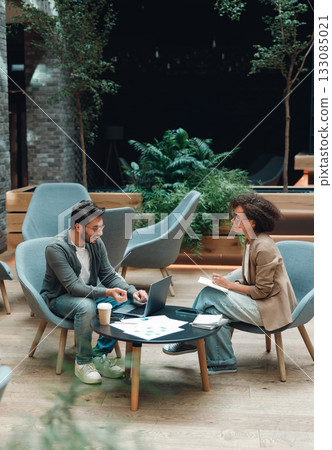 enthusiastic rehearsal of pitch with printed slides and instructor guidance in cozy lounge 133085021