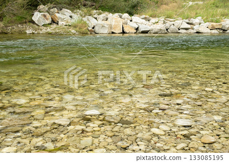 Close-up of a turbulent mountain river with a rocky bottom and shore 133085195