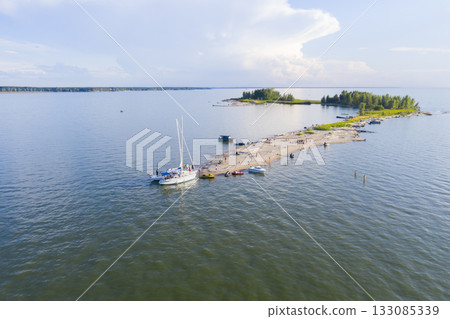 Aerial view of the yachts moored at the sandy spit of the lake with the edges of the forest 133085339