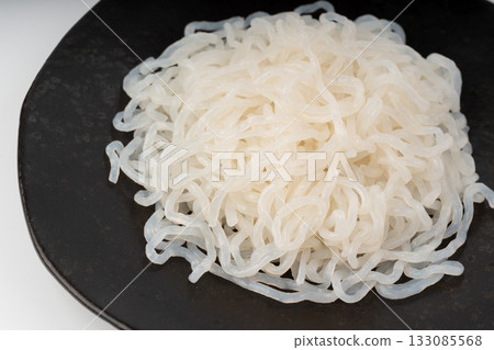 Shirataki or konnyaku pasta on black plate close up. Konjak jelly noodles 133085568