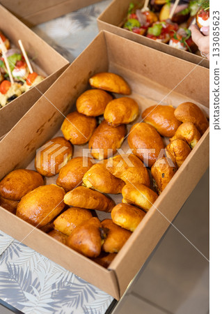 Catering box with fresh baked savory pastries, ready for takeaway, delivery or buffet Catering box with fresh baked savory pastries, ready for takeaway, delivery or buffet 133085623