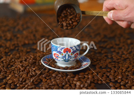Male hand pouring Turkish coffee. cup of coffee with beans Male hand pouring Turkish coffee. cup of coffee with beans 133085844