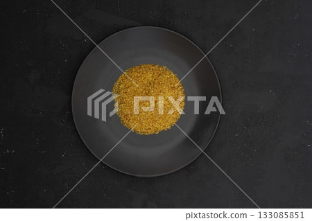 Bulgur wheat in a black plate on black background. Top view, copy space. Flat lay. 133085851