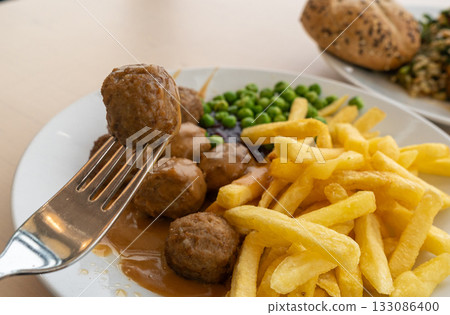 Meatballs with french fries, green peas, bechamel sauce and cranberry jam Meatballs with french fries, green peas, bechamel sauce and cranberry jam 133086400
