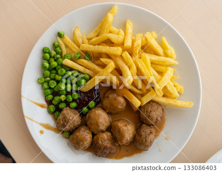 Meatballs with french fries, green peas, bechamel sauce and cranberry jam 133086403