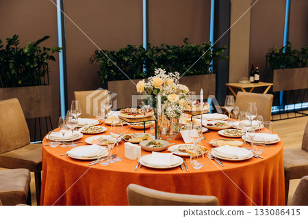 Elegant banquet table with floral centerpiece, candles and appetizers in restaurant Elegant banquet table with floral centerpiece, candles and appetizers in restaurant 133086415