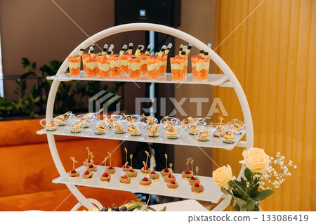Gourmet canapes and verrines on a tiered stand at an elegant catered event 133086419