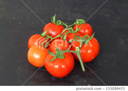 Fresh cherry tomatoes on a black background. Bunch of fresh cherry tomato on a black background 133086455