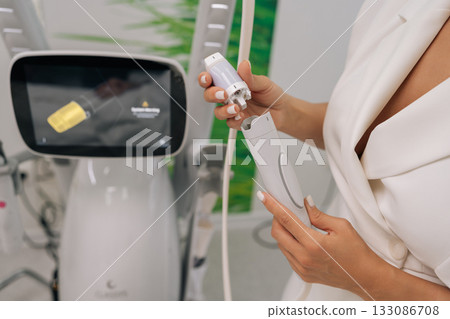 Close-up of professional cosmetologist connecting specialized microneedle device, offering innovative beauty procedures and anti-aging solutions in modern aesthetic clinic. 133086708