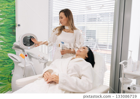 Portrait of cosmetic doctor performing mesotherapy microneedling on woman face, providing skin rejuvenation and professional cosmetic care in clinic. Concept of facial anti-aging, skincare treatment. Portrait of cosmetic doctor performing mesotherapy microneedling on woman face, providing skin rejuvenation and professional cosmetic care in clinic. Concept of facial anti-aging, skincare treatment. 133086719