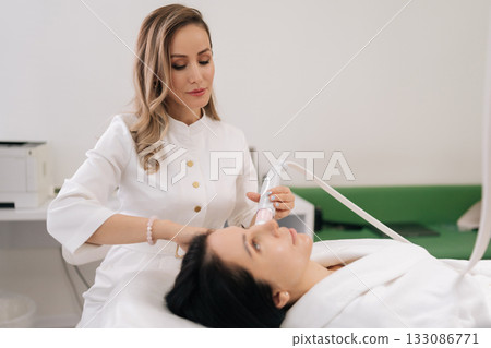 Portrait of skilled cosmetologist performing mesotherapy microneedling treatment on woman face, applying advanced skincare technology for professional beauty and anti-aging procedures in clinic. Portrait of skilled cosmetologist performing mesotherapy microneedling treatment on woman face, applying advanced skincare technology for professional beauty and anti-aging procedures in clinic. 133086771