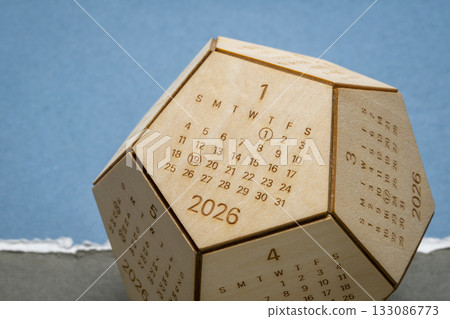 January 2026 - small wooden dodecahedron desktop calendar against art paper, time and business concept 133086773