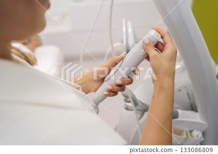 Closeup of professional cosmetologist female connecting specialized microneedle device, offering innovative beauty procedures and anti-aging solutions in modern aesthetic clinic. 133086809