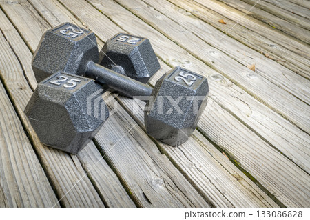 a pair of heavy cast iron hex dumbbells on a grained barn wood background, fitness concept a pair of heavy cast iron hex dumbbells on a grained barn wood background, fitness concept 133086828