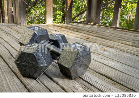a pair of heavy cast iron hex dumbbells on a grained barn wood background, fitness concept a pair of heavy cast iron hex dumbbells on a grained barn wood background, fitness concept 133086830