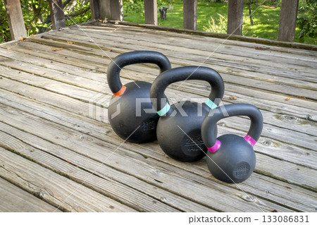 iron kettlebells on a wooden backyard deck, home gym concept iron kettlebells on a wooden backyard deck, home gym concept 133086831