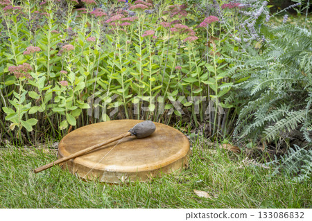 handmade, native American style, shaman frame drum covered by goat skin with a beater in a backyard handmade, native American style, shaman frame drum covered by goat skin with a beater in a backyard 133086832