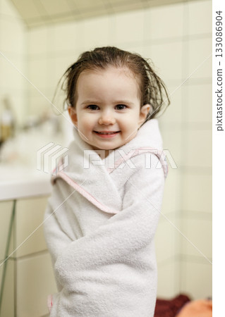 Smiling toddler girl wrapped in towel after bath Smiling toddler girl wrapped in towel after bath 133086904
