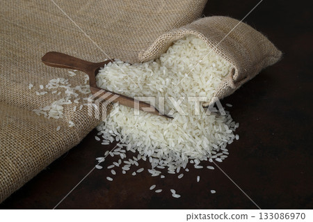 Bag with long rice and spoon stands on wooden background 133086970
